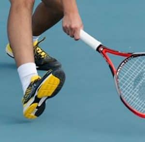 joueur portant des baskets de tennis noir et jaune