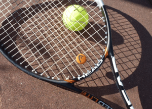raquette de tennis et balle posées par terre