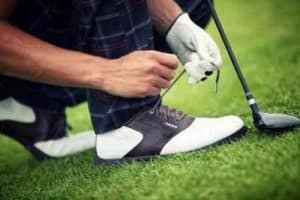 homme nouant ses chaussures de golf à lacets