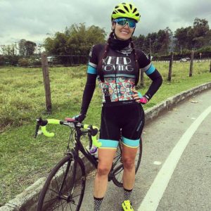 femme en tenue de cycliste debout devant son vélo