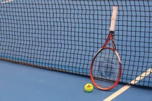 raquette et balle de tennis posées sur court en moquette