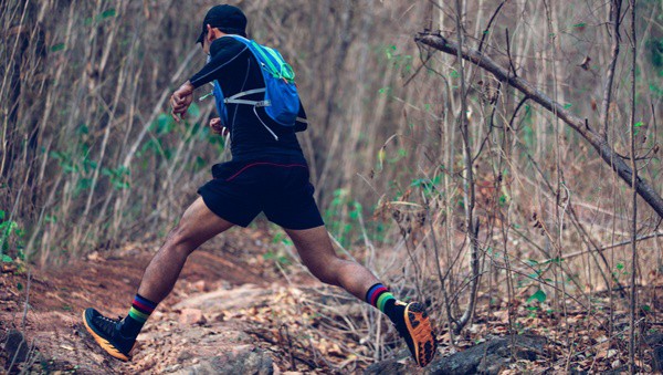 Homme de dos qui court un trail dans la forêt