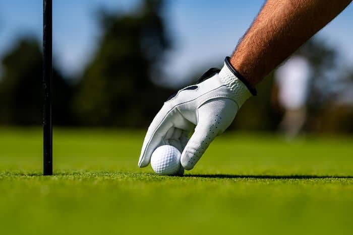 joueur de golf plaçant la balle sur le green en portant en gant de golf