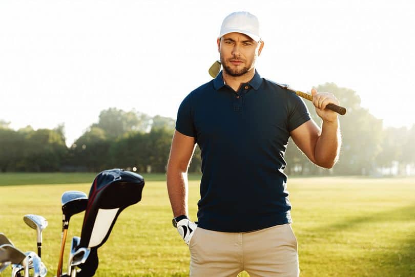 joueur de golf qui tient son club dans une tenue elegante