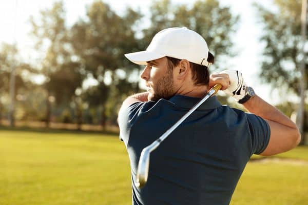 joueur de golf avec casquette et club sur le green